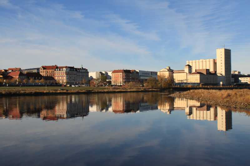 Die Silhouette einer Stadt spiegelt sich in der Morgensonne im Wasser. 