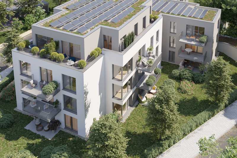 Blick von schräg oben auf ein modernes rechtwinklig gebautes Mehrfamilienhaus mit Dachterrassen und großen Fensterfronten und Balkonen.