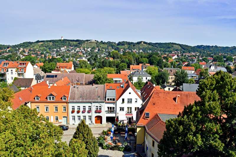 Blick von oben auf eine Altstadt mit kleinen Häusern und einer Straße aus Backsteinpflaster.